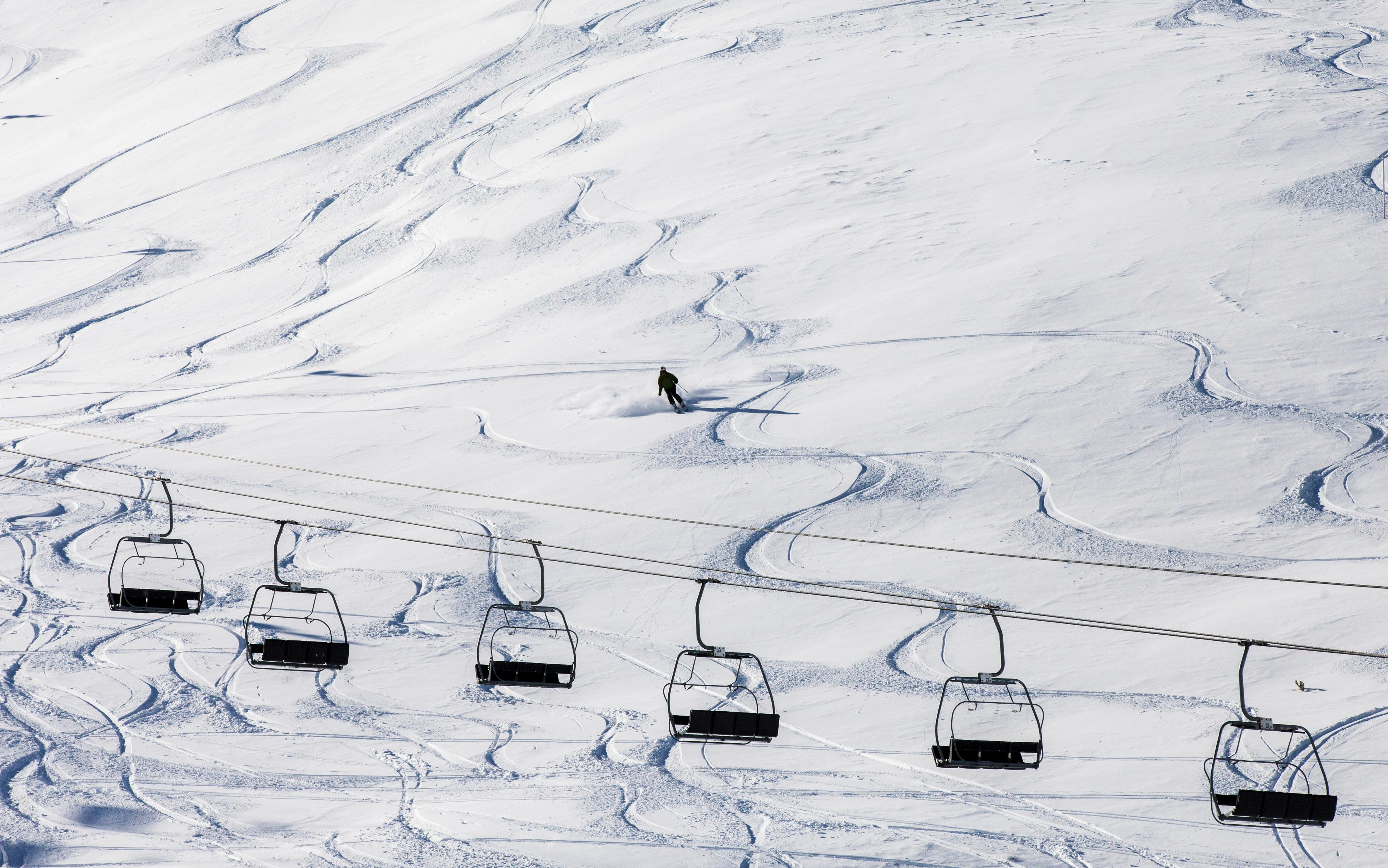 Skiier Skiing down off piste slope with chairlift in foreground in Andorra